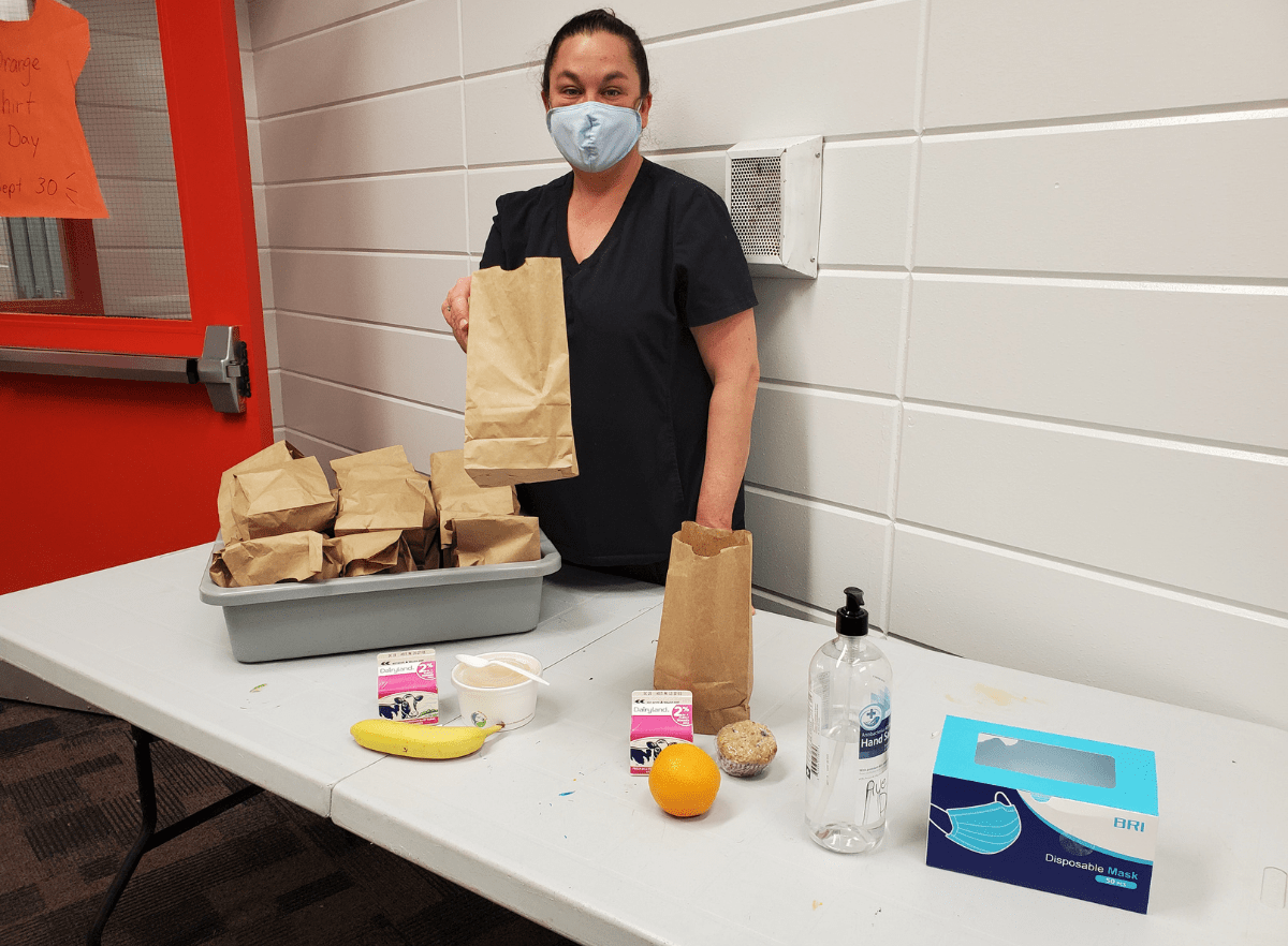 Lady with paper brown bags and breakfast itmes like oranges, bananas, muffins