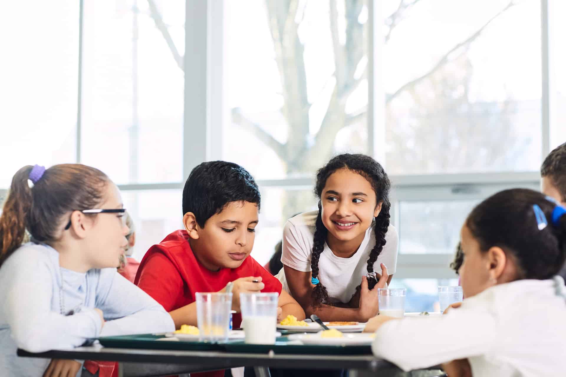 Children sitting around a cafeteria table talking