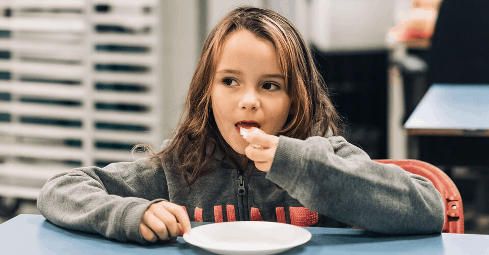 Child with long hair eating a piece of bread