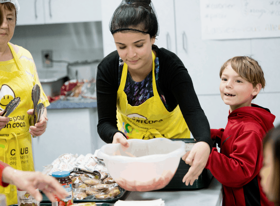 Volunteers with child making breakfast